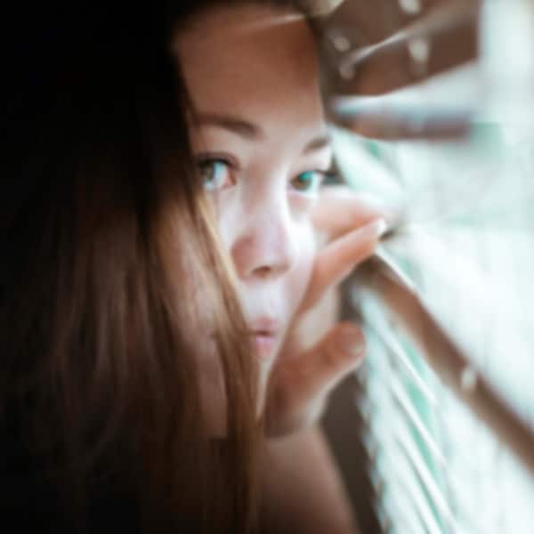 Frau schaut aus Fenster, soziale Isolation